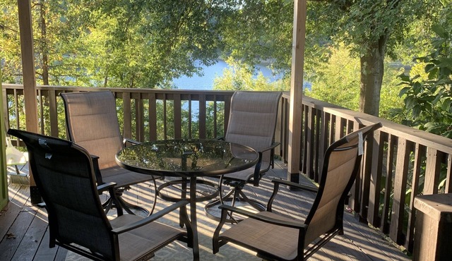 Lakeside house with fireplace, deck, and a fenced backyard with firepit.